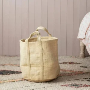 Handwoven natural jute storage basket with handles on bohemian rug